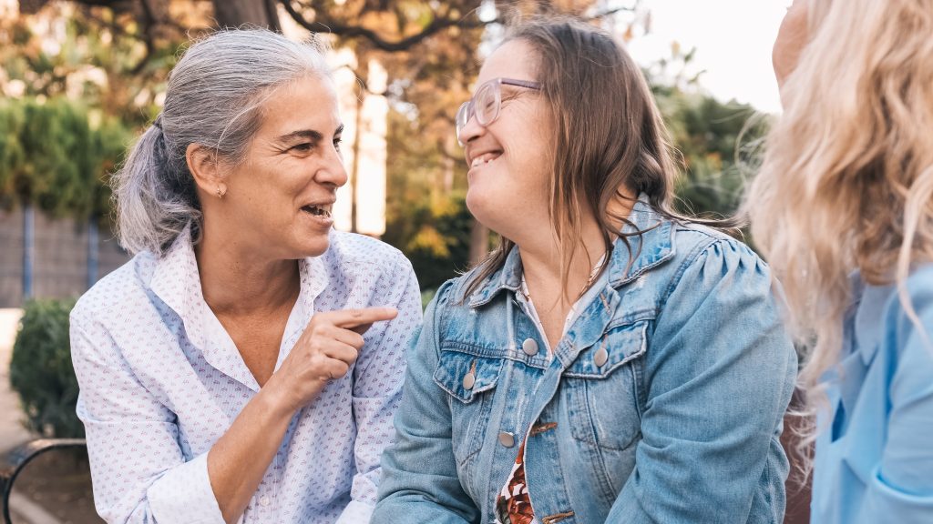 Happy woman with down syndrome enjoying a conversation with two other women